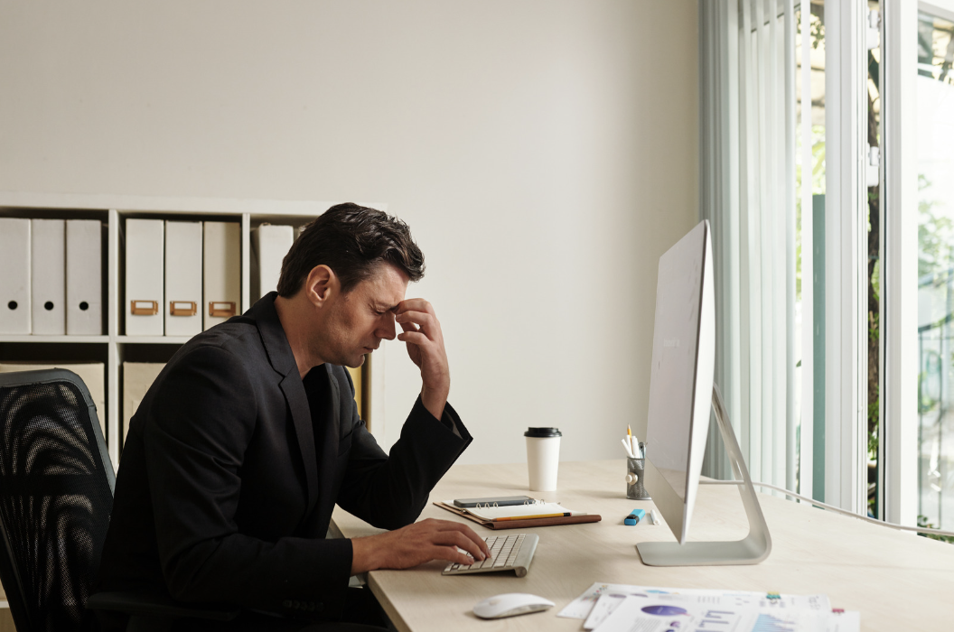 Man sitting at his computer with his head in his hands
